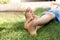 child sits on the lawn in the summer his bare feet are tickled with a large ostrich feather