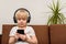 Child is sitting on couch with headphones and stares at phone. Kids and gadgets addiction concept