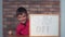 Child sitting at the desk holding flipchart with lettering day o