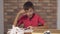 Child sitting at the desk holding flipchart with lettering idea on the background red brick wall