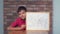 Child sitting at the desk holding flipchart with lettering staff