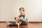 Child sitting on the floor putting on his socks with an expression of effort, concept of autonomy