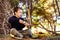 A child sitting on the ground in a forest uses a stick to draw on the ground and experience nature