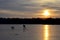 A child skates and runs after a dog on the ice of a lake against the background of snowdrifts, forests and sunset