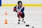 Child skating with a puck at ice hockey practice