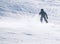 Child skiing down a steep alpine piste with snow spraying up behind him