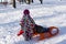 Child with sled on winter background. Child sledding