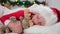 Child sleeping before Christmas. Little boy in Santa hat and Christmas pajamas lying in white bed hugging plush toy at