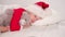 Child sleeping before Christmas. Little girl in Santa hat and Christmas pajamas lying in white bed hugging teddy bear at