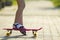 Child slim legs in white socks and black sandals on plastic pink skateboard on bright sunny summer blurred copy space pavement