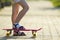 Child slim legs in white socks and black sandals on plastic pink skateboard on bright sunny summer blurred copy space pavement