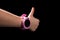 Child with smart watch and thumb up. Pink smart watch  on black. Girl`s hand with pink smsart watch