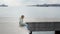 Child with smartphone sitting on sea pier and swaying legs