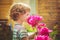 Child smelling bouquet of peonies, sun backlighting. Toning photo.