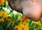 Child Smelling a Yellow Flower