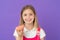Child smile with donut on violet background. Little girl with glazed ring doughnut. Happy kid with junk food on purple