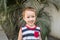 A child smiles in front of some plants