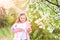 Child smiling with bunny ears in garden with blossoming trees