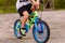 A child in sneakers pedaling a two-Wheeler on the asphalt in the summer. only feet on the pedals of the bike