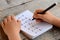 Child solves math examples. Child holds a marker in his hand and writes answers to multiplication examples in a notebook