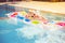 The child splashes on an inflatable colorful mattress in the pool.