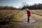 Child splashing in a puddle with wellies in country landscape