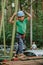 Child in sports equipment, a protective helmet stopped near a tree, holding a rope with his hands. Portrait of a brave boy