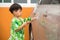 A child spraying water to wash a car