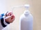 A child sprays her hands with antiseptic from a plastic spray bottle. Hands with a bottle close-up on a blue background