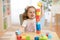 Child stacks building cubes sitting at table in nursery