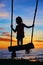 Child stand on swing on colorful sunset sky background