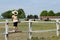 Child standing on corral and watching horses