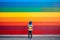 A child standing on front of rainbow colored wall. Child mental health concept. ASD, autism spectrum disorder awareness concept.