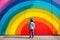 A child standing on front of rainbow colored wall. Child mental health concept. ASD, autism spectrum disorder awareness concept.