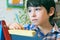 Child standingnext to the easel. Kid boy learn paint by brush in class school. Kindergarten interior on background. Boy