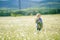 A child stands in a fragrant field with white daisies on the background of summer Alpine mountains.