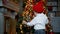 Child stands in front of a Christmas tree with toys near the fireplace