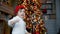 Child stands in front of a Christmas tree with toys near the fireplace