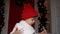 Child stands on the porch steps in the snow in a white sweater and a red hat