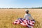 Child in straw hat holding american flag in golden field with wheat