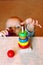 Child stretches hand behind multicolored wooden toy developing