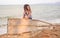 Child in a striped marine t-shirt on the broken boat on the seashore