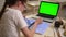 Child student painting picture on paper, laptop with green screen tutorial Spbas. Rear view of girl