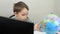 A child studies a world map on a globe. Distance learning during the lockdown on pandemic isolation. Distance education.