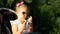 Child in sunglasses is sitting in a stroller and eats an apple at sunset. Portrait baby girl close-up on a sunny day.