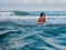 Child surfing in the blue sea under a cloudy sky