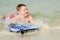 Child surfing on bodyboard at beach