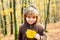 Child in sweater in the autumn nature, warm sunny weather on fall background.