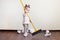 Child sweeps broom with paper bins in the apartment, household chores