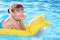 Child swimming on inflatable beach mattress.